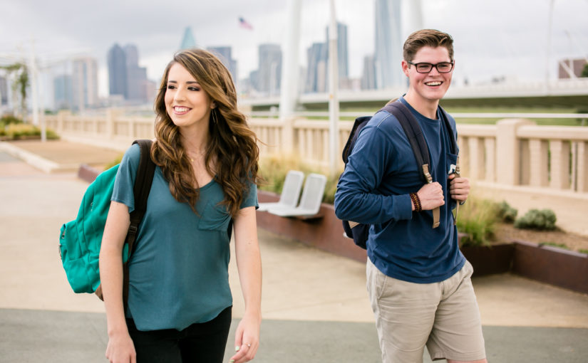 Two coeds walking across a downtown Dallas bridge on an overcast day.