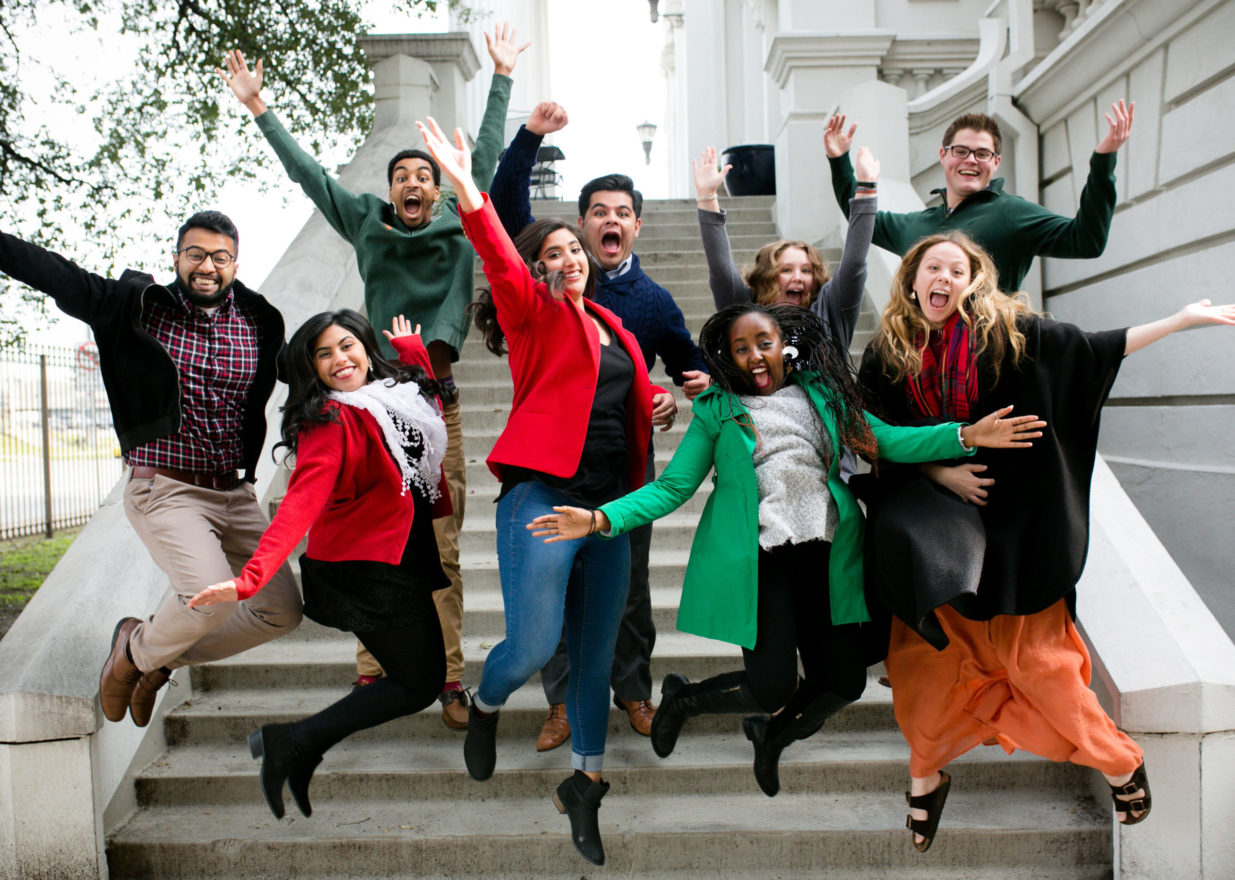 Nine wildly happy students caught arms flying, mid-jump off the library steps.